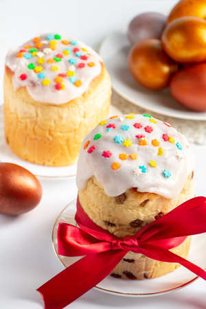 Easter cake panettone with sweet icing and golden eggs on white plate. Happy spring holiday.
