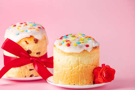 Delicious Easter cakes panettone decorated with ribbon and flowers on pink background. Festive food.