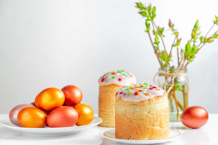 Easter cake panettone with sweet icing and golden eggs on white plate. Happy spring holiday.