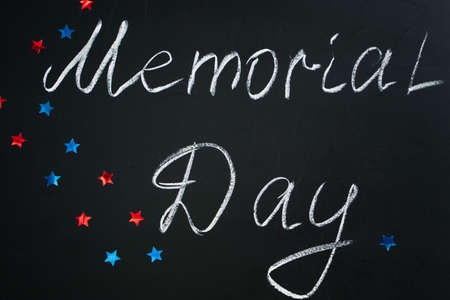 Handwritten inscription Memorial Day on a black chalkboard and American blue and red stars on the background. Holiday concept.の写真素材