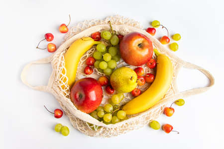 Organic ripe fruits in eco-friendly mesh bag on a white background. Trendy string bag for shopping....