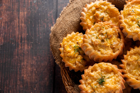 Basket with fresh muffins on a wooden background. Homemade cakes with vegetables and cheese. Recipe for autumn seasonal dish. Rural rustic style.の写真素材