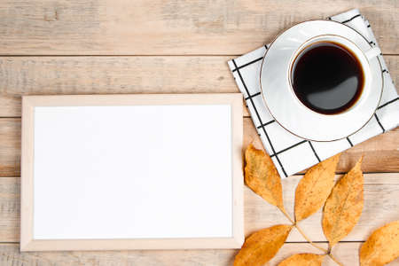 Autumn flat lay. Cup of hot espresso coffee and fallen yellow leaves on wooden background. Empty frame mock up for text. Morning concept. Copy space.の写真素材