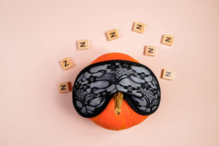Sleeping pumpkin on a pink background. Halloween and autumn time concept.の写真素材