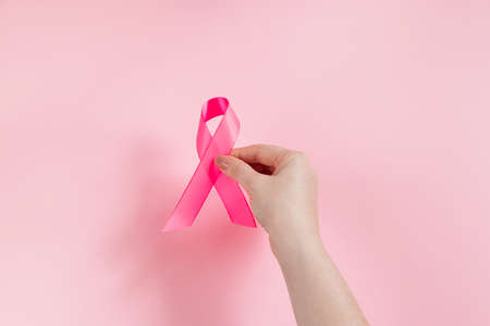 Breast Cancer Awareness Month. Woman's hand holds pink ribbon. Health care concept, cancer control symbol. Copy space.の写真素材