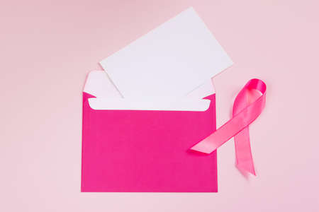 Pink ribbon on colored background. Breast Cancer Awareness Month symbol. Women's health care concept. Promotion of campaign to fight cancer. Copy space.の写真素材