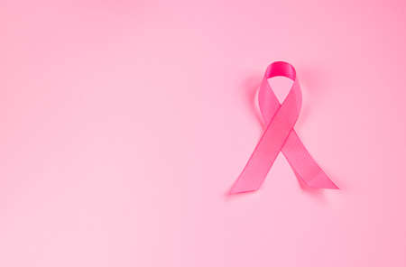 Pink ribbon on colored background. Breast Cancer Awareness Month symbol. Women's health care concept. Promotion of campaign to fight cancer. Copy space.の写真素材