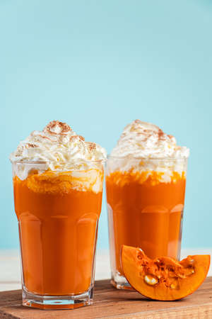 Pumpkin spicy latte with whipped cream on a blue background. Two glasses of hot autumn drink.の写真素材