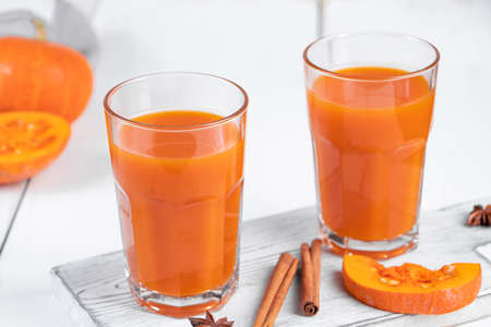 Two glasses of pumpkin juice on white wooden background. Vegetable detox drink for healthy diet. Vegan smoothie.の写真素材