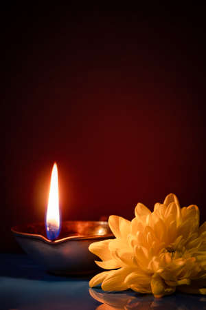Happy Diwali. Traditional symbols of Indian festival of light. Burning diya oil lamps and flowers on red background. Copy space, vertical photo.の写真素材