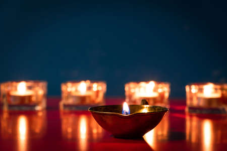 Happy Diwali. Burning diya oil lamps and flowers on blue background. Traditional Indian festival of light. Celebrating religious holiday.の写真素材