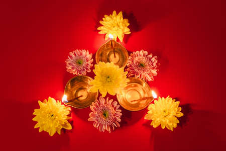 Happy Diwali. Traditional Hindu celebration. Diya oil lamps and flowers on red background. Religious holiday of light. Copy space.の写真素材