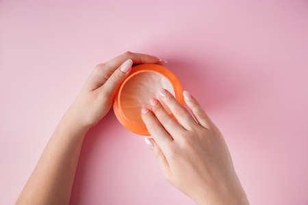 Nourishing cream and beautiful female hands on a pink background. Skin care concept. Image for advertising and design.の写真素材