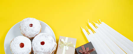 Happy Hanukkah. Jewish dessert Sufganiyot on yellow background. Symbols of religious Judaism...