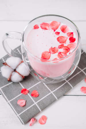 Pink matcha with rose petals on a white background. Transparent cup with trendy vegan whipped tea. Moon milk. Relaxing drink for sleepy time.の写真素材