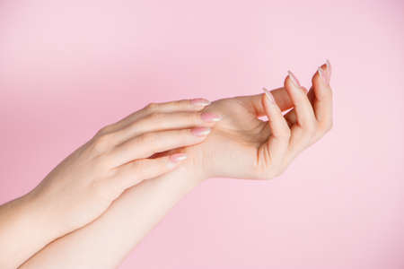 Skin care concept. Beautiful female hands on a pink background. Place for textの写真素材
