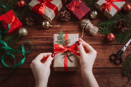 Wrapping Christmas gifts. Woman ties a bow on the box.の写真素材