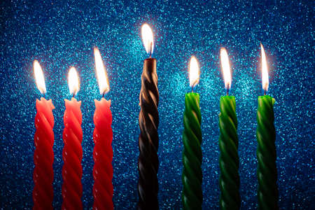 Celebration of African American Kwanzaa holiday. Seven burning candles in traditional kinara candlestick on blue glittering background.の写真素材