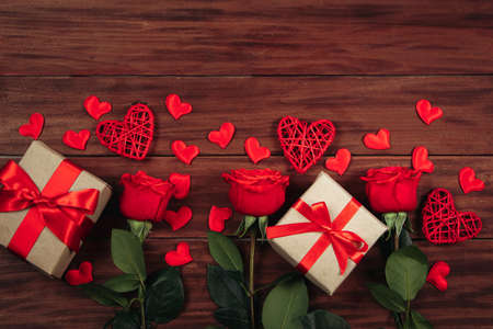 Red roses and hearts on dark wooden background. Valentine's day postcard concept.