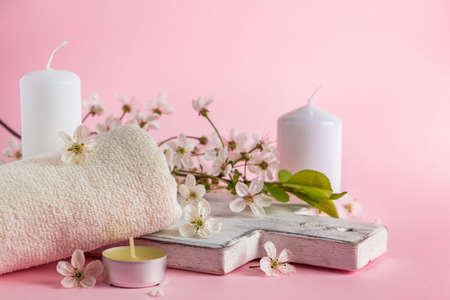 Natural cosmetic products for spa and aromatherapy. Relaxation concept. Candles, flowers and a towel on a pink background. Place for your text.の写真素材