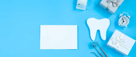 Happy International Dentist Day. Paper cut mockup of tooth and dental tool on blue background. Dental care concept. Greeting card for professional holiday. Banner format.の写真素材