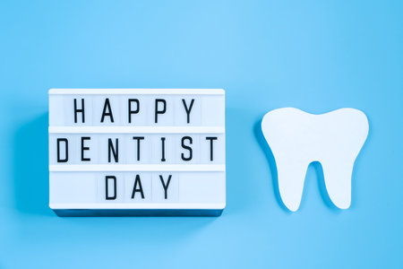 Happy International Dentist Day. Paper cut mockup of tooth and dental tool on blue background. Dental care concept. Greeting card for professional holiday. Copy space.の写真素材