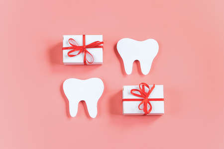 Happy dentist day. Paper cut mockup of tooth and gift boxes on pink background. Dental care concept. Greeting card. Copy space.の写真素材