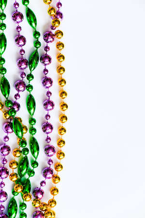 Mardi Gras background. Multicolored beads on white background. Fat Tuesday symbol. Festive decorations in gold, green and purple colors for traditional holiday. Copy space.の写真素材