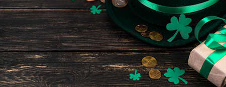 Leprechaun hat and shamrock clover leaves on brown wooden background. Happy St. Patricks Day. Place...