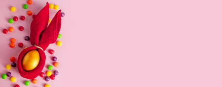 Happy Easter. Gold eggs and candies on a pink background. Place for text. Banner format