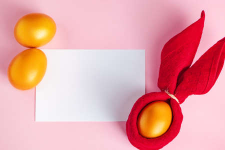 Glittery golden Easter eggs and blank greeting card on pink background. Happy spring holiday.の写真素材