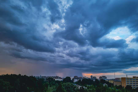 Storm clouds close up. Dramatic sky over city. Thunderstorm weather. Rain pours from cumulus clouds.の写真素材