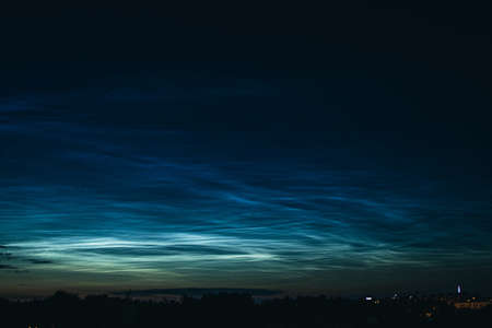 Noctilucent mesospheric clouds in night sky. Rare atmospheric phenomenon over city. Astronomy and meteorology.の写真素材