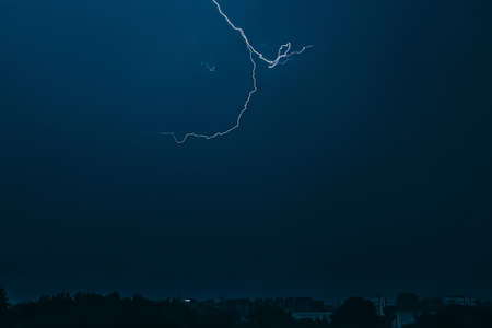 Lightning in sky over city. Bright flashes on dark night. Thunderclouds and electricity discharges...