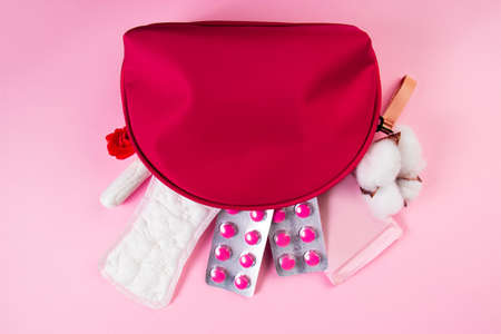 Pink cosmetic bag and set of feminine hygiene products for menstruation. Sanitary pads, tampons, pills. Womens health concept. Copy space.の写真素材