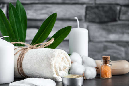 Wellness accessories on gray stone background. Towel, candles and aromatic salt. Face and body care...