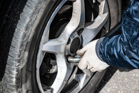 Auto mechanic changes wheel on old car. Man changes punctured tire after breakdown. Emergency roadside assistance. Automobile wheel close-up.の写真素材