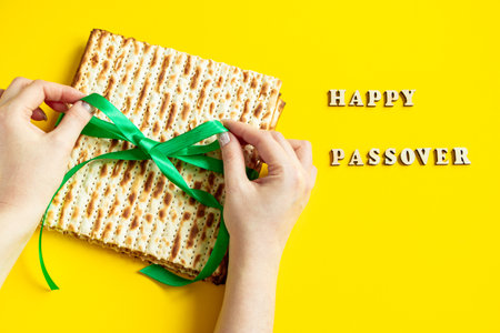 Woman is holding matzah. Celebrating the traditional Jewish holiday of Passover or Pesach. Matzo on yellow background.の写真素材