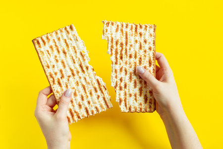 Woman is holding matzah. Celebrating the traditional Jewish holiday of Passover or Pesach. Matzo on yellow background.の写真素材