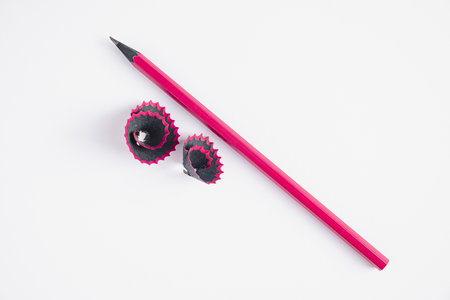 Wooden pink pencil and shavings on white background. Sharpening graphic pencil for drawing. Symbol of creativity, copy space.の写真素材