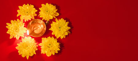 Diwali Indian Light Festival. Diya oil lamp and yellow flowers on red background. Traditional Hindu...