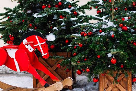 Christmas decorations on porch of house. Festive tree with red Christmas balls and wooden red horse. Holiday season, street decor.の写真素材