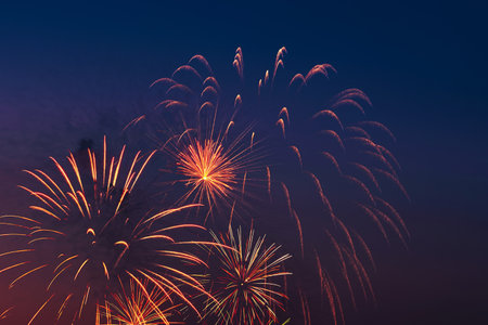 Bright colored fireworks on blue sky background. Celebration and holidays concept. New Year, Independence Day, July 4 Festival. Bright explosions of lights in the sky.の写真素材