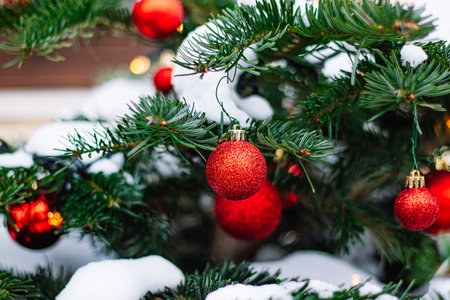 Red Christmas balls and garlands on branch. Christmas tree with decor. Holiday season, street decorations.の写真素材