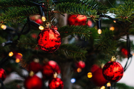 Red Christmas balls and garlands on branch. Christmas tree with decor. Holiday season, street decorations.の写真素材