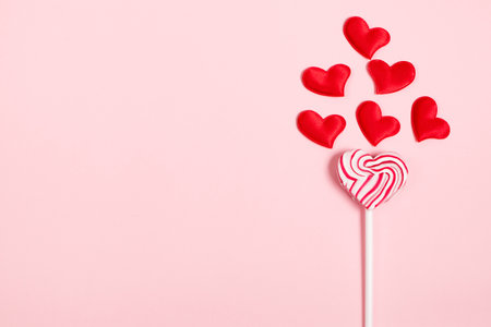 Lolipop and red hearts on pink background. Valentine's day concept.の写真素材