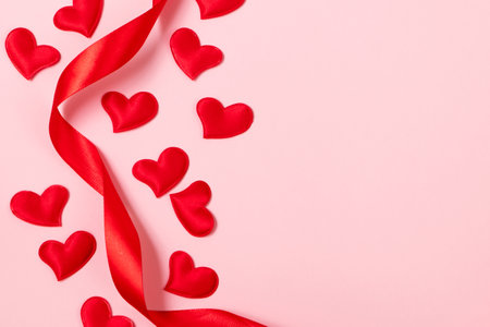 Red silk ribbon and hearts on pink background. Valentine's day, place for text.の写真素材