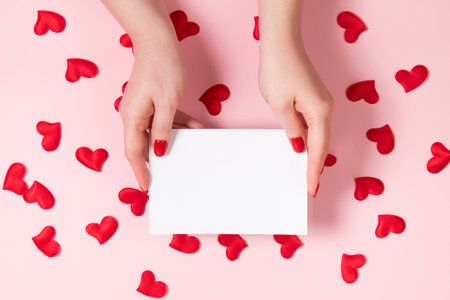 Female hands hold greeting card for valentine's day. Place for your text.の写真素材