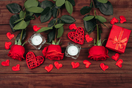 Gift boxes in craft paper and red roses on wooden background. Valentine's day, place for text.の写真素材