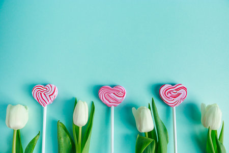Tulips and lolipop in shape of heart on blue background. Valentine's day concept, banner format.の写真素材